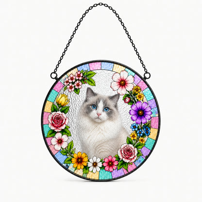 A circular stained-glass-style hanging ornament featuring a white and gray cat in the center, surrounded by colorful flowers and pastel tiles, suspended by a black chain against a light gray background.
