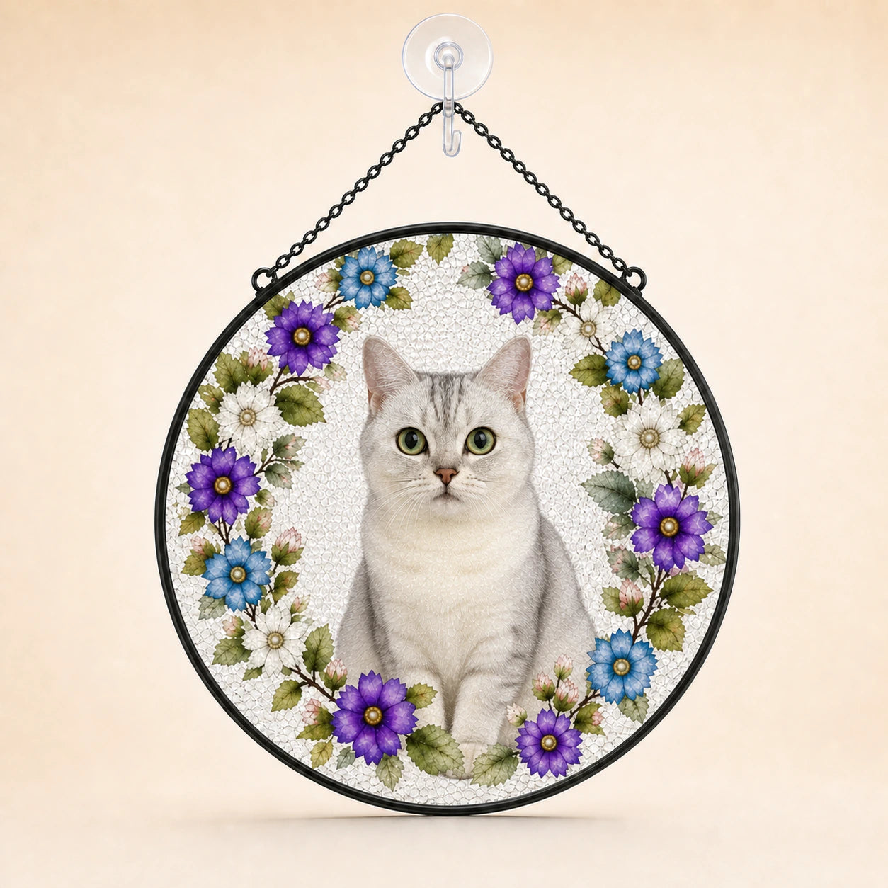 Round hanging wall art featuring a white cat centered within a floral wreath of purple, blue, and white flowers, suspended by a black chain from a clear wall hook against a warm beige background.