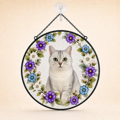 Round hanging wall art featuring a white cat centered within a floral wreath of purple, blue, and white flowers, suspended by a black chain from a clear wall hook against a warm beige background.